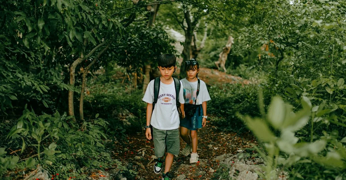 Deux enfants profitent d'une promenade dans une forêt verte et luxuriante, capturant l'essence de l'aventure en plein air.