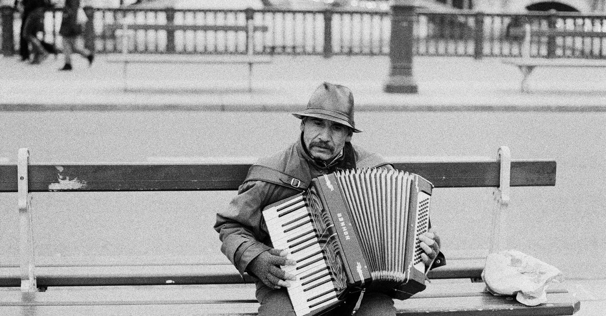 Un musicien de rue joue de l'accordéon sur un banc à Paris, France.