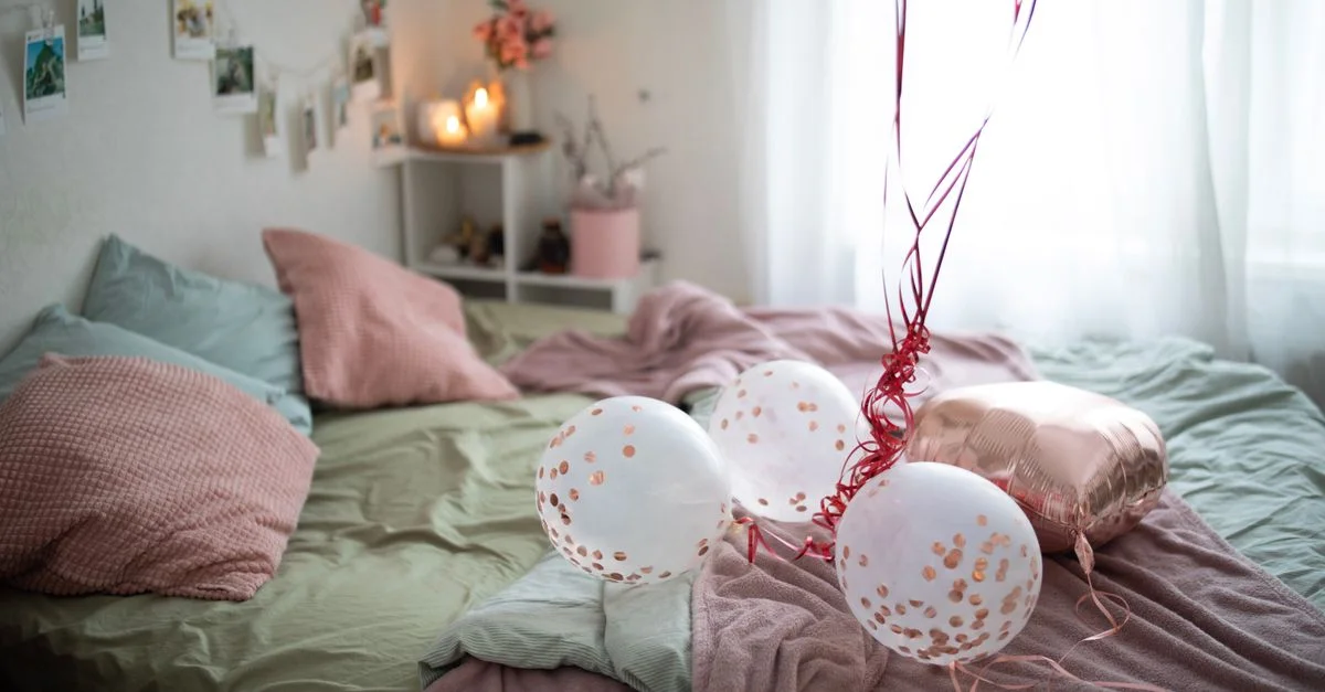 Une scène de chambre confortable avec des ballons, un éclairage doux et une literie confortable, parfait pour les célébrations.